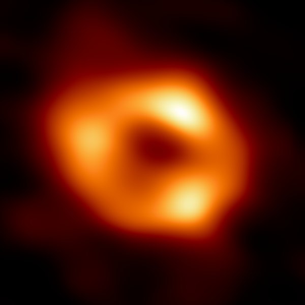 Image montrant le trou noir Sagittarius a*. C'est une grosse boule orangée avec trois zones plus brillantes en périphérie, réparties de façon régulières.